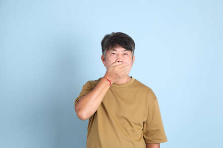 The senior Asian man with casual clothes standing on the blue background.の写真素材