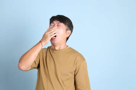 The senior Asian man with casual clothes standing on the blue background.の写真素材