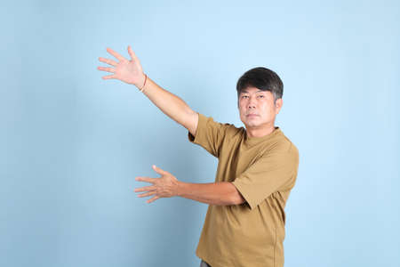 The senior Asian man with casual clothes standing on the blue background.の写真素材