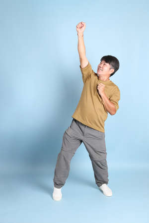 The senior Asian man with casual clothes standing on the blue background.の写真素材