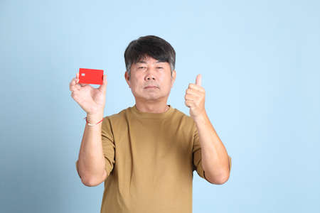 The senior Asian man with casual clothes standing on the blue background.の写真素材