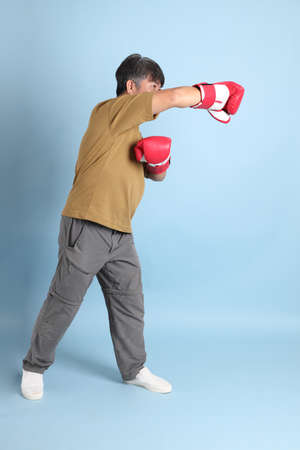 The senior Asian man with casual clothes standing on the blue background.の写真素材