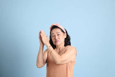 The senior Asian woman with brown dressed standing on the blue background.の写真素材