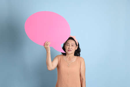 The senior Asian woman with brown dressed standing on the blue background.の写真素材
