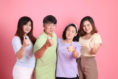 The happy Asian family standing on the pink background.の写真素材