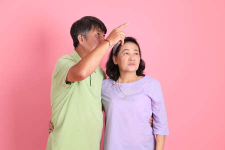 The senior Asian couple with casual clothes standing on the pink background.の写真素材