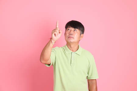 The senior Asian man with casual clothes standing on the pink background.の写真素材