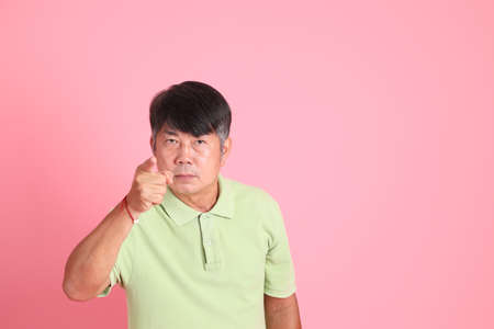 The senior Asian man with casual clothes standing on the pink background.の写真素材