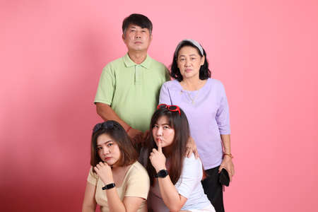 The Asian family in casual clothes standing on the pink background.の写真素材