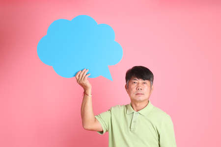 The senior Asian man with casual clothes standing on the pink background.