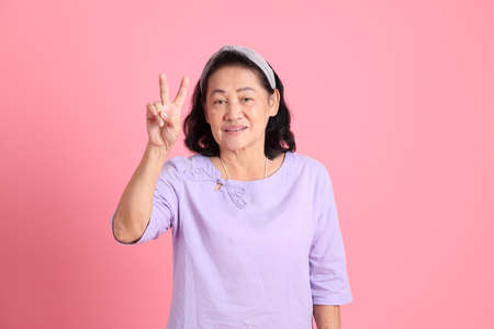 The senior Asian woman with brown dressed standing on the Pink background.の写真素材