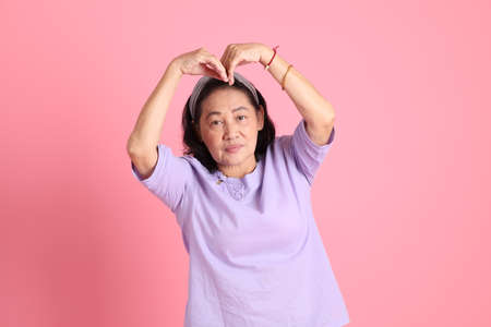 The senior Asian woman with brown dressed standing on the Pink background.の写真素材