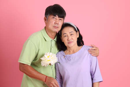 The senior Asian couple with casual clothes standing on the pink background.の写真素材