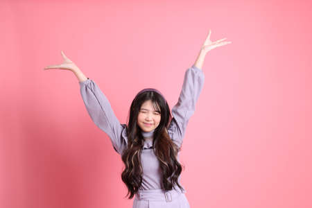 The cute young Asian woman with preppy dressed standing on the pink background.