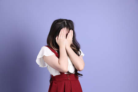 The cute young Asian woman with preppy dressed standing on the purple background.