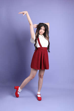 The cute young Asian woman with preppy dressed standing on the purple background.の写真素材
