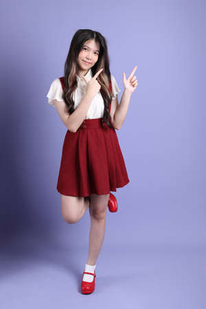 The cute young Asian woman with preppy dressed standing on the purple background.の写真素材