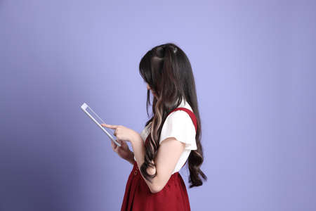 The cute young Asian woman with preppy dressed standing on the purple background.