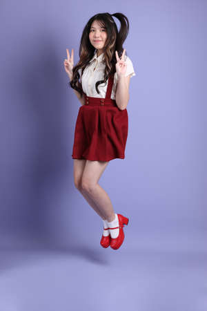 The cute young Asian woman with preppy dressed standing on the purple background.の写真素材