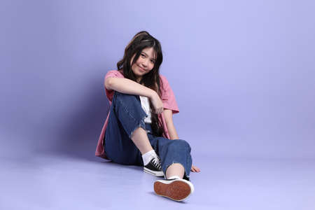 The cute young Asian girl with casual clothes standing on the purple background.の写真素材