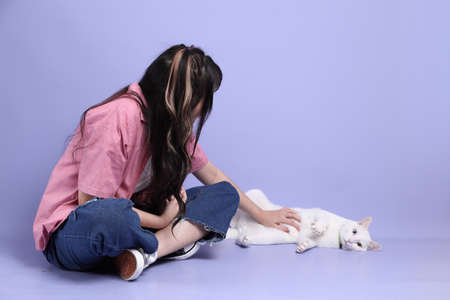 The cute young Asian girl with casual clothes standing on the purple background.の写真素材
