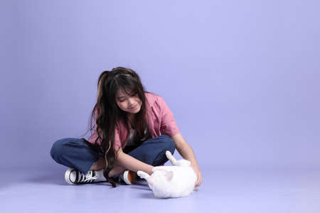The cute young Asian girl with casual clothes standing on the purple background.の写真素材