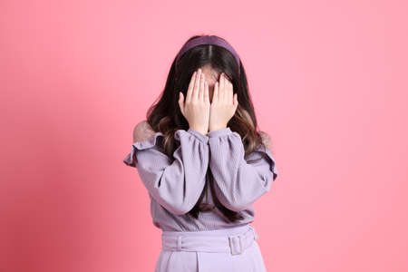 The cute young Asian woman with preppy dressed standing on the pink background.