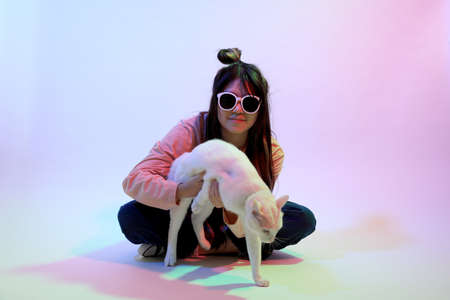 The cute young Asian girl with casual clothes posing under the gel color lightning in studio.