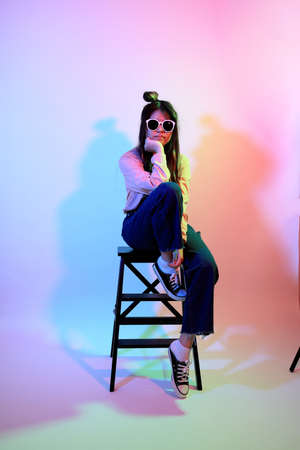 The cute young Asian girl with casual clothes posing under the gel color lightning in studio.の写真素材