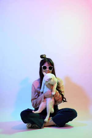 The cute young Asian girl with casual clothes posing under the gel color lightning in studio.