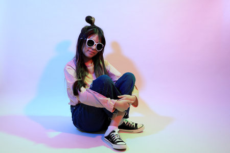 The cute young Asian girl with casual clothes posing under the gel color lightning in studio.の写真素材