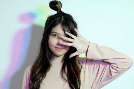 The cute young Asian girl with casual clothes posing under the gel color lightning in studio.の写真素材