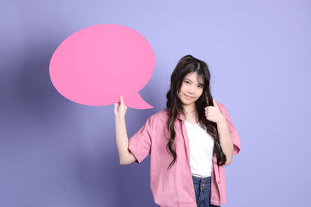 The cute young Asian girl with casual clothes standing on the purple background.の写真素材