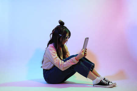 The cute young Asian girl with casual clothes posing under the gel color lightning in studio.の写真素材