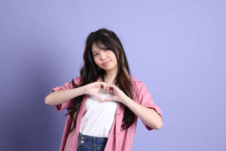 The cute young Asian girl with casual clothes standing on the purple background.の写真素材