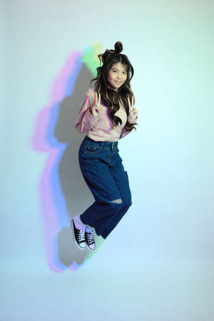 The cute young Asian girl with casual clothes posing under the gel color lightning in studio.の写真素材