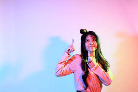 The cute young Asian girl with casual clothes posing under the gel color lightning in studio.の写真素材
