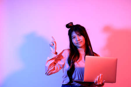 The cute young Asian girl with casual clothes posing under the gel color lightning in studio.