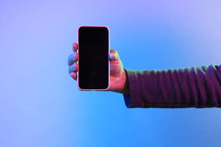 The Asian man hands holding the smart phone under the vivid color.の写真素材