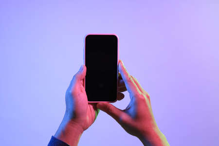 The Asian man hands holding the smart phone under the vivid color.の写真素材