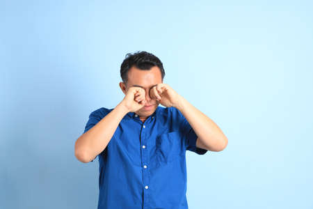The Asian middle aged man with blue shirt standing on the blue background.