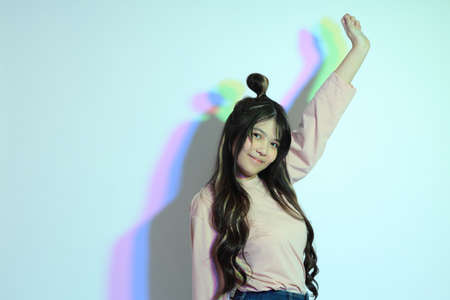 The cute young Asian girl with casual clothes posing under the gel color lightning in studio.