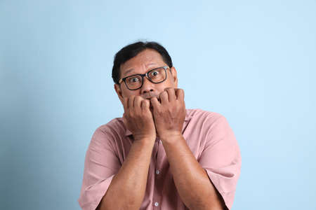 The adult Asian man with pink shirt standing on the blue background.の写真素材