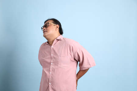 The adult Asian man with pink shirt standing on the blue background.の写真素材