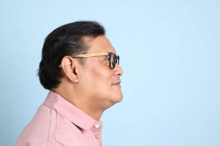 The adult Asian man with pink shirt standing on the blue background.の写真素材