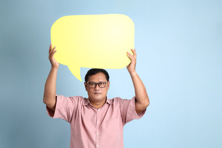 The adult Asian man with pink shirt standing on the blue background.