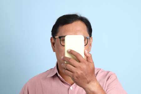 The adult Asian man with pink shirt standing on the blue background.