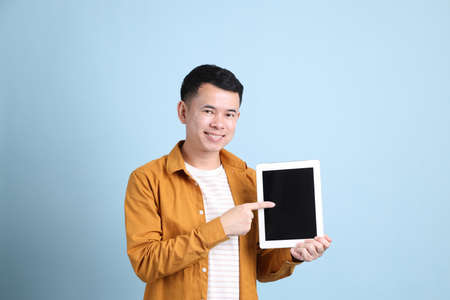 The Asian LGBTQ man with yellow shirt standing on the blue background.