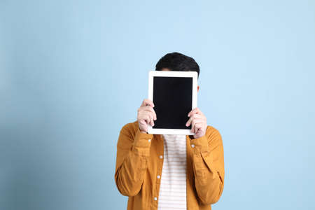 The Asian LGBTQ man with yellow shirt standing on the blue background.