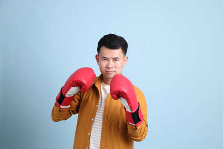 The Asian LGBTQ man with yellow shirt standing on the blue background.の写真素材
